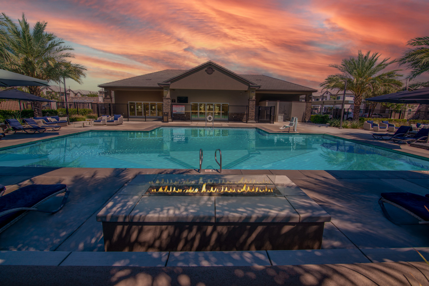 The after photograph of the same recreational area vividly demonstrates enhancements, featuring a spectacular sky, reflections in the pool, and visible flames in the fire, creating an inviting and captivating environment that beckons viewers to live here.